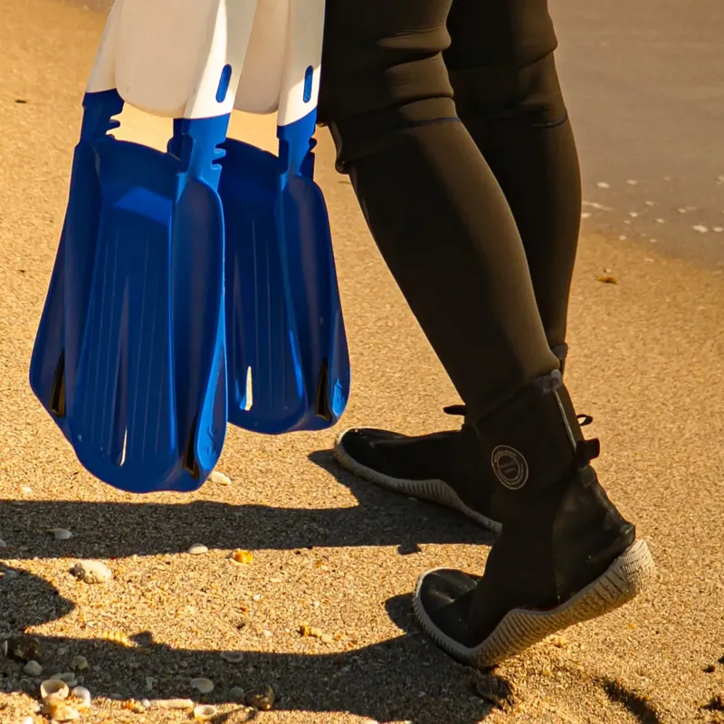 צולל הולך בנעלי הצלילה ונושא סנפירים כחולים
